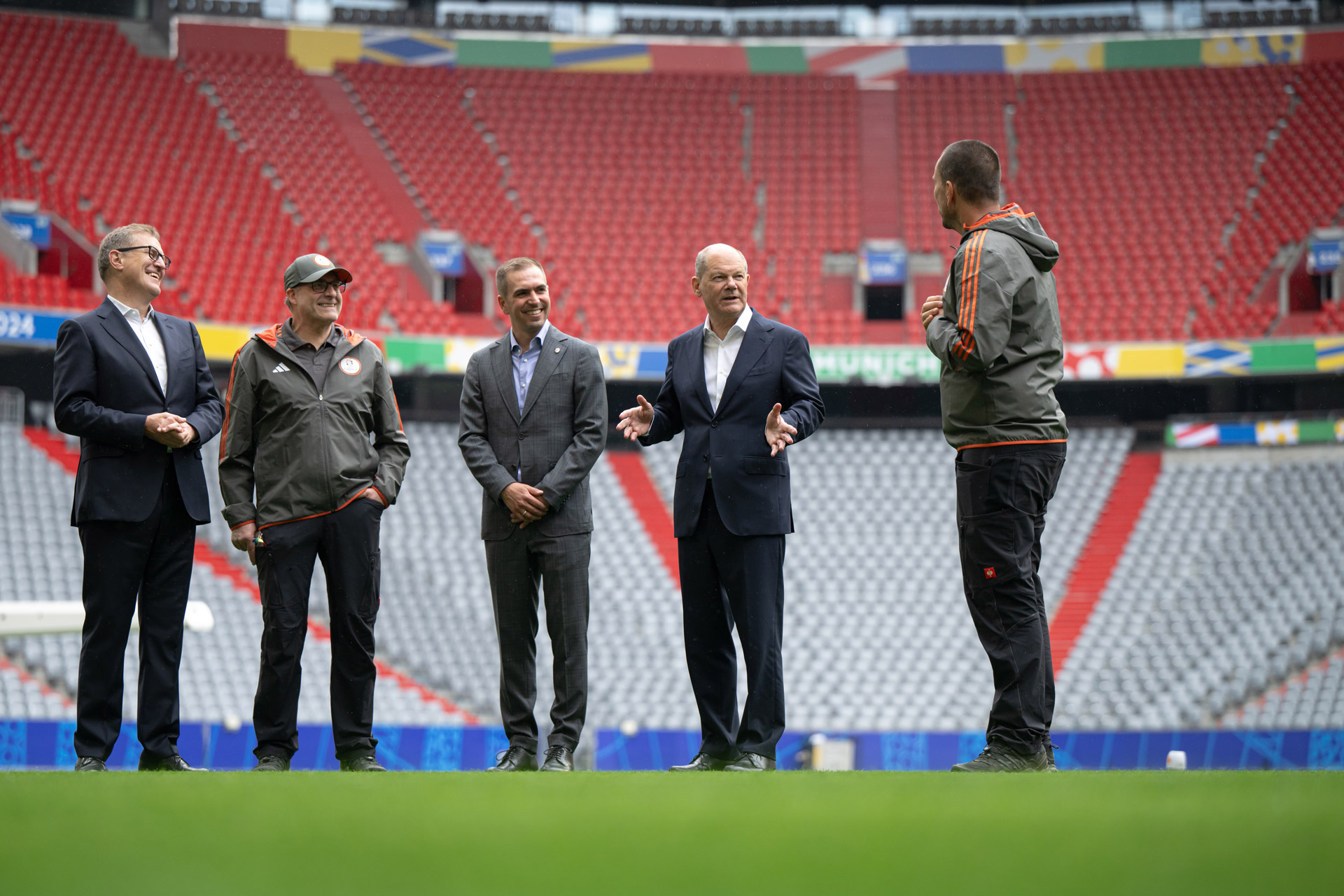 Bundeskanzler Olaf Scholz spricht mit dem Greenkeeper der Arena in München.